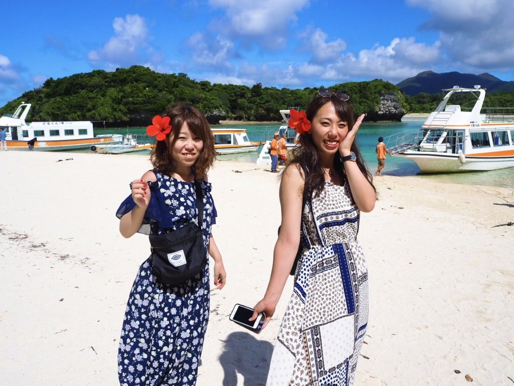 石垣島の川平湾公園のビーチで、エメラルドグリーンの海と真っ白なビーチ散策を楽しむ女性たち